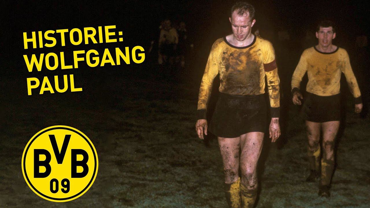 Vorschaubild aus BVB History: Zwei Spieler in verschmutzten gelben Trikots gehen über den Platz, daneben der Titel Historie: Wolfgang Paul